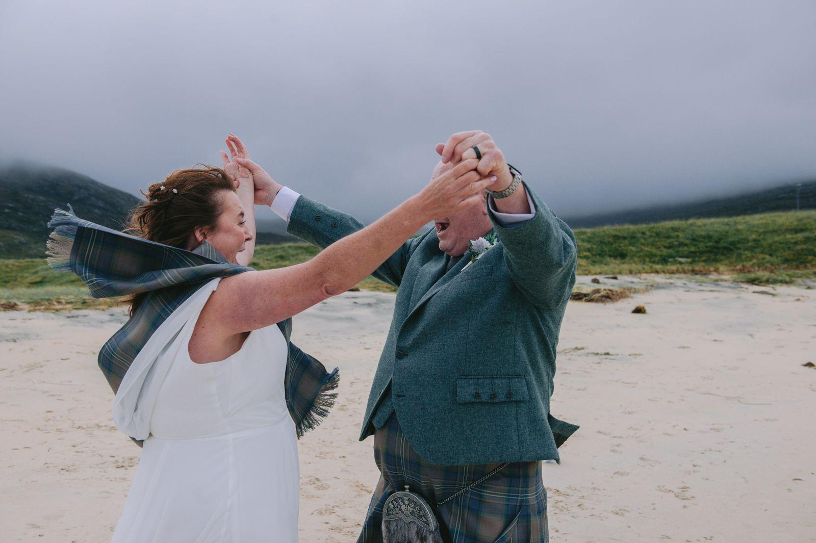 Bride and groom raising their arms in celebration after their wedding ceremony on Seilebost beach