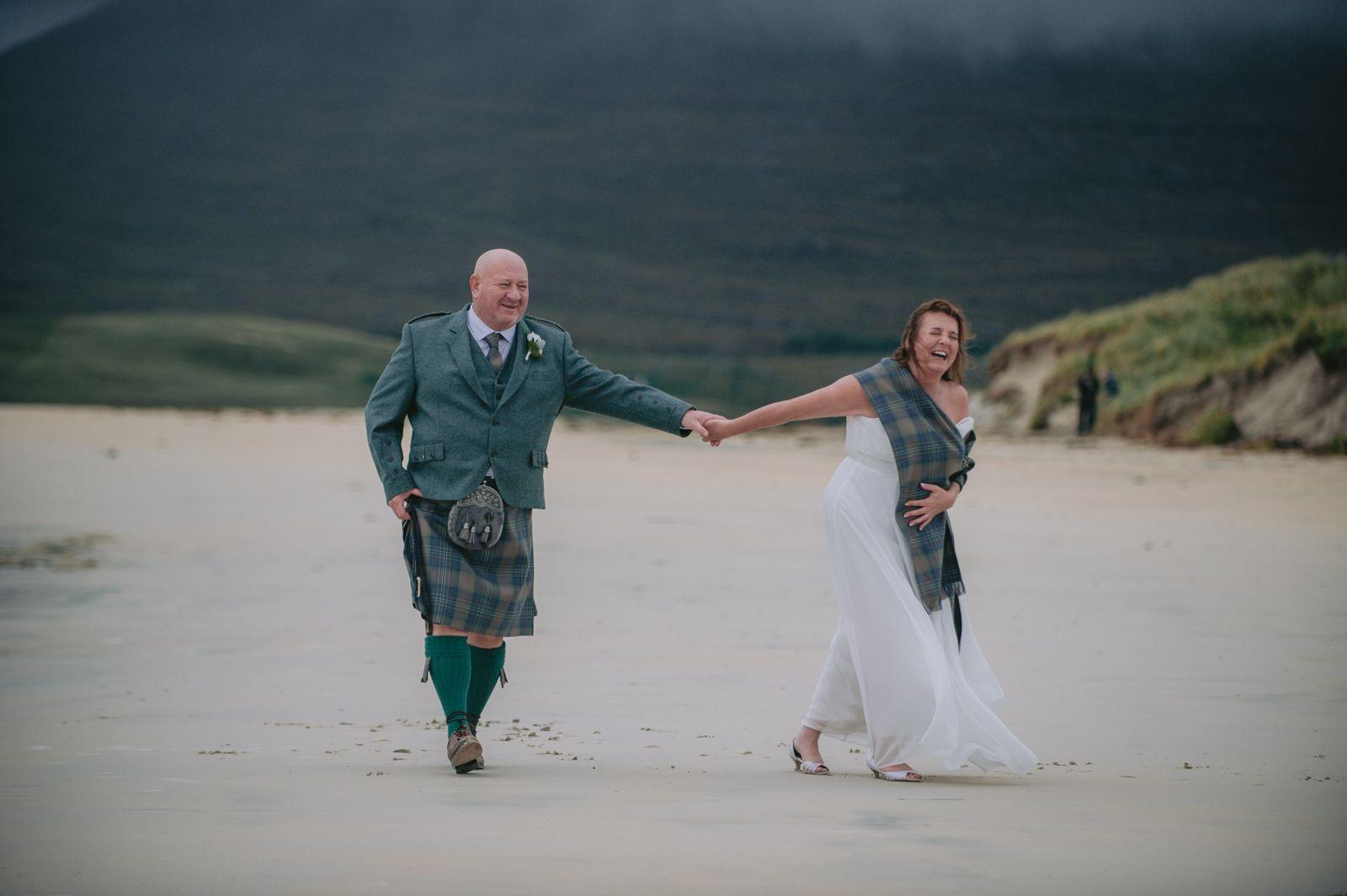 Bride and groom holding hands and dancing on Seilebost beach after their humanist wedding