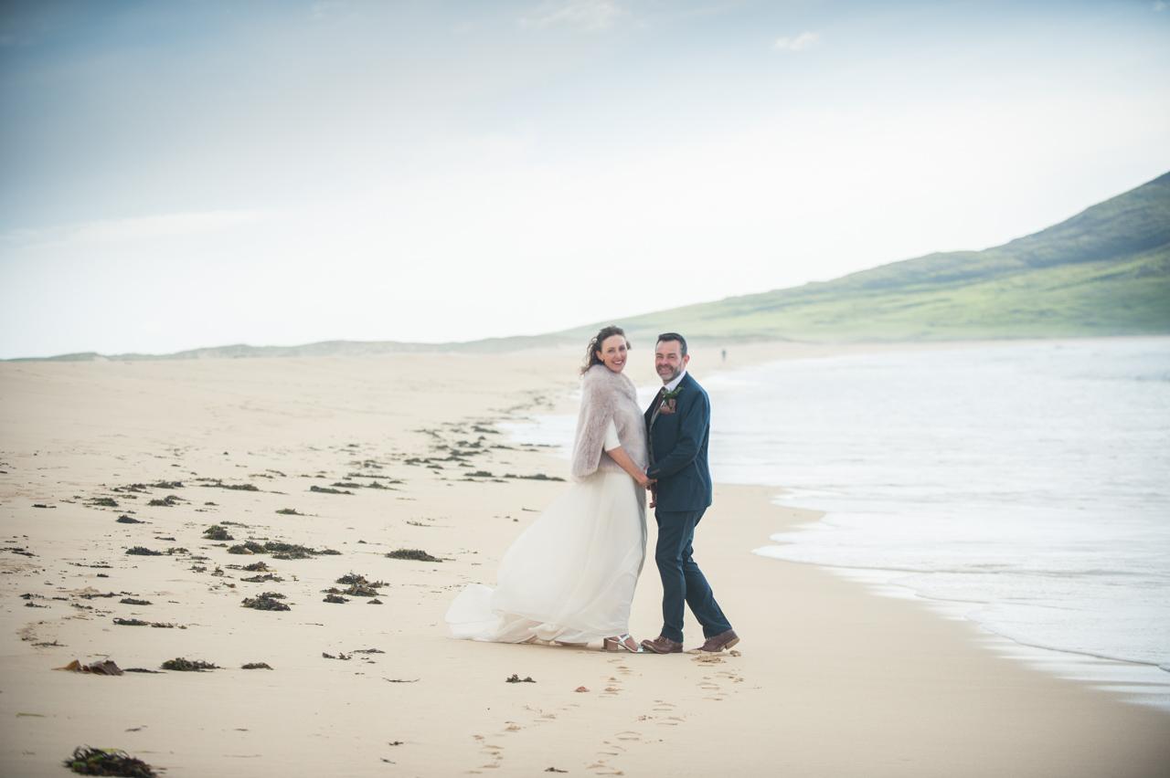 Newlyweds Emma and Jamie face each other for a wedding portrait on Scarista Beach on the Isle of Harris. 
