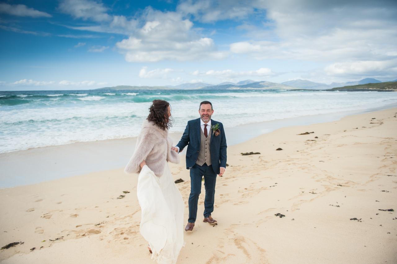 Bride and groom Emma and Jamie hold hands on Scarista Beach after their intimate wedding on the Isle of Harris.