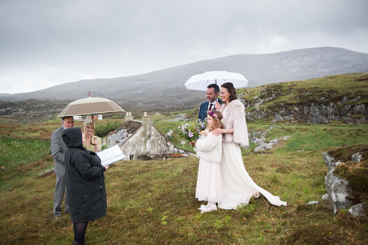 Emma and Jamie share an umbrella for their Isle of Harris wedding in the rain. 