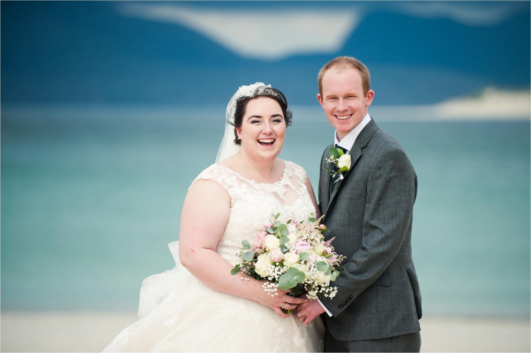Bride and groom Lauren and Michael are all smiles against the green and blue of the waves at Horgabost Beach on the Isle of Harris. 
