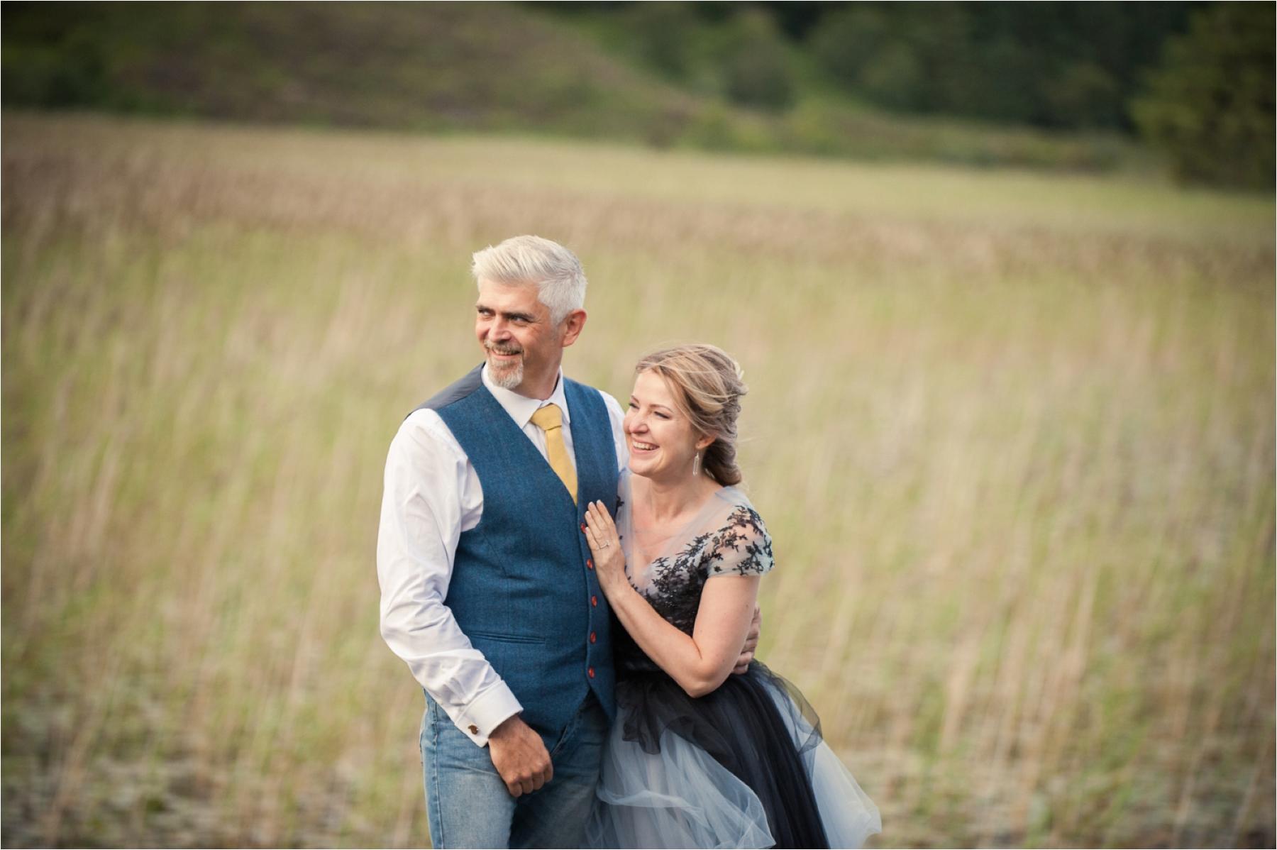 A bride and groom stand in a field for wedding portraits on the Isle of Skye. 