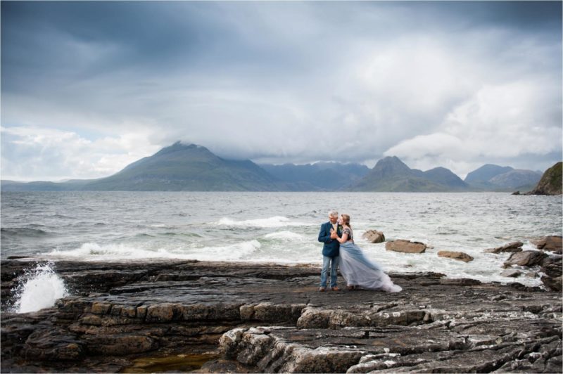 A bride and groom stand on the edge of Loch Coruisk on the Isle of Skye on their wedding day.