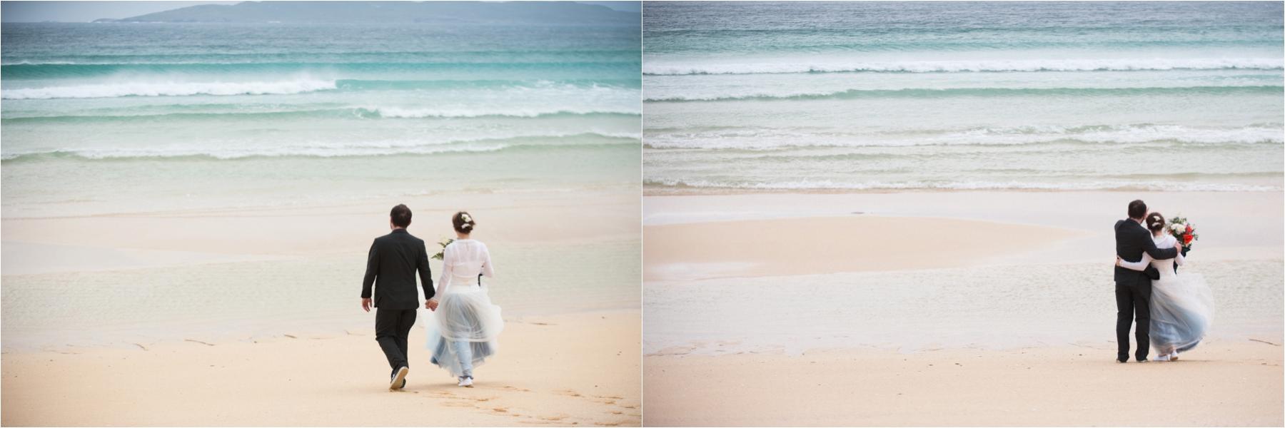 Scottish islands elopement wedding photography with a bride and groom on a deserted beach, waves crashing behind them. 