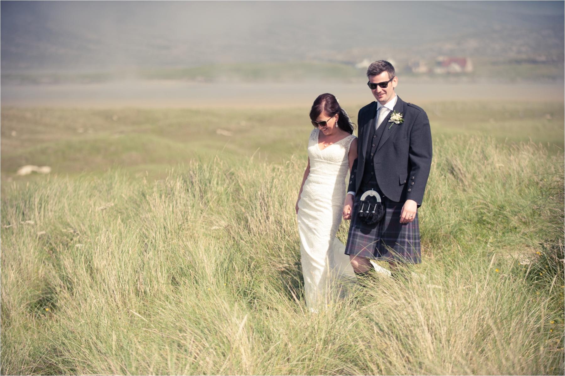 A bride and groom wear sunglasses for wedding portraits near Scarista Beach on the Isle of Harris. 