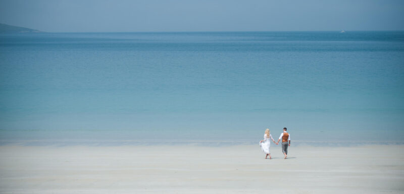 Isle of Harris elopement - a bride and groom are small figures on the beach after their outdoor ceremony.