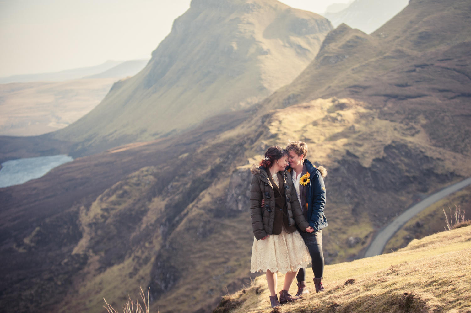 A bride and groom stand on a craggy hillside on the Isle of Skye