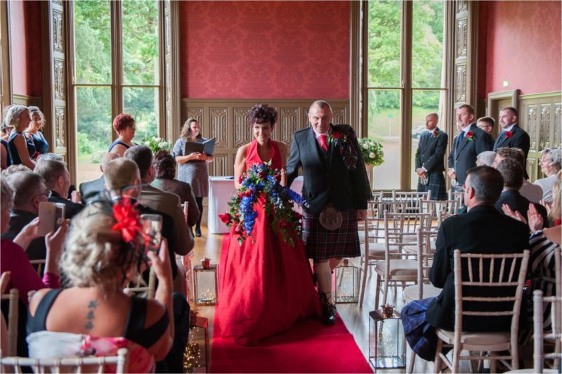 A bride in a red dress and her groom on their wedding day at Lews Castle in the Scottish western isles.