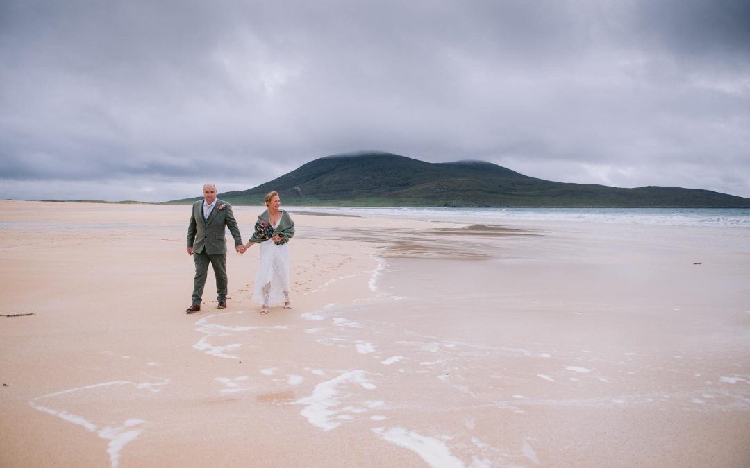 Newlyweds standing at the water's edge on Scarista Beach, Isle of Harris