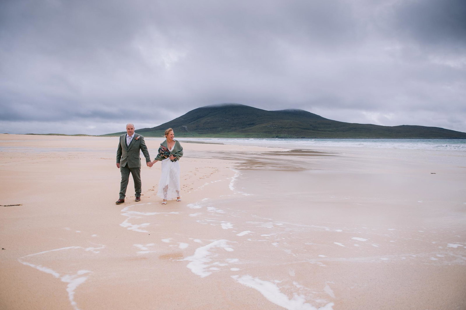 Newlyweds standing at the water's edge on Scarista Beach, Isle of Harris