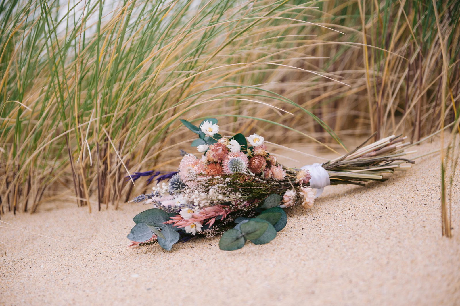 Wildflower wedding bouquet resting in the sand at Scarista Beach elopement, Isle of Harris