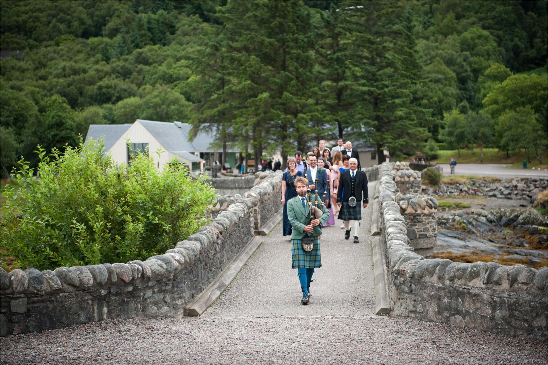 A piper leads guests into Eilean Donan Castle for a wedding ceremony. 