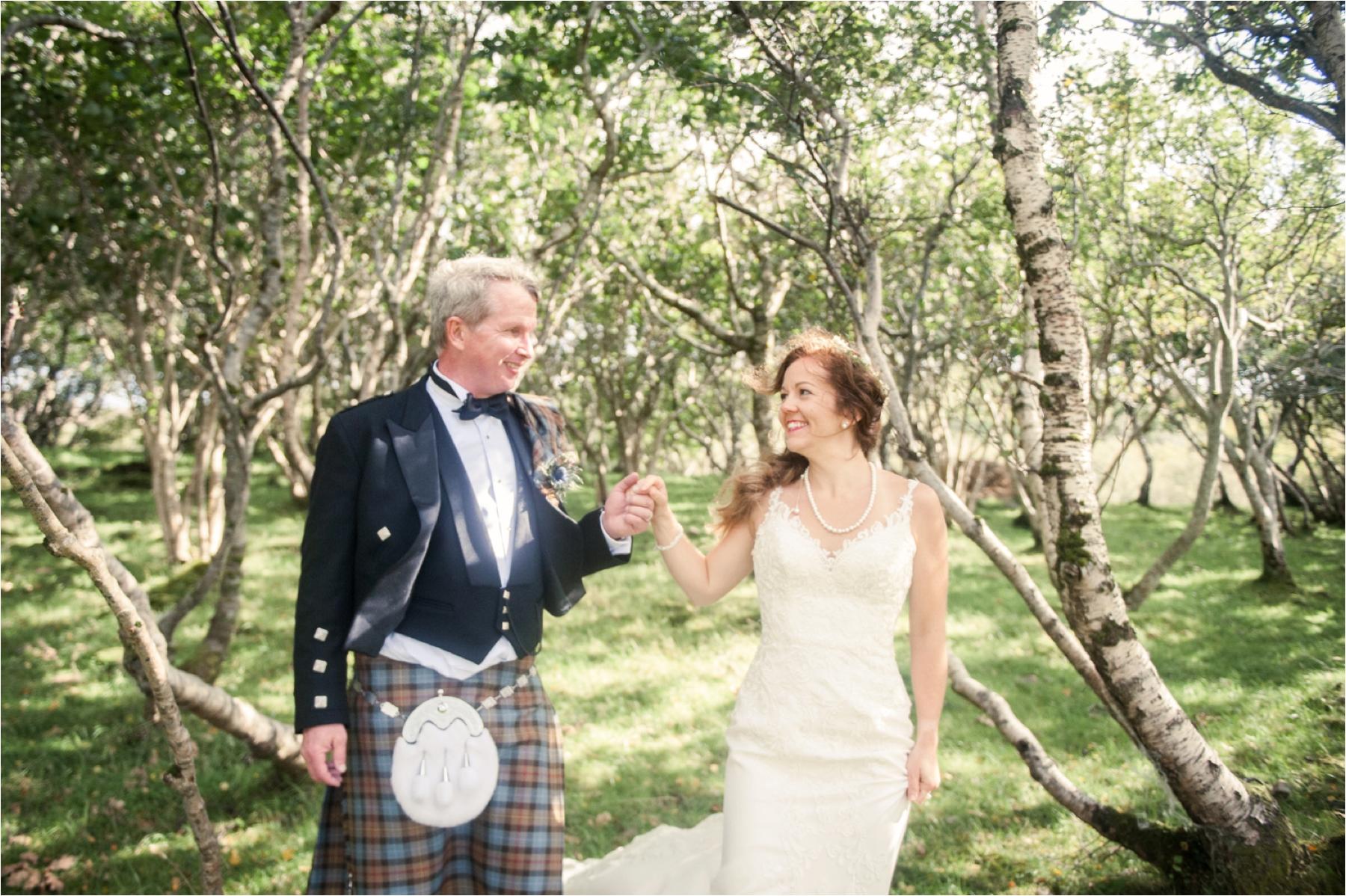 A bride and groom hold hands after their humanist wedding ceremony at Dunscaith Castle on the Isle of Skye in the Scottish Highlands. 